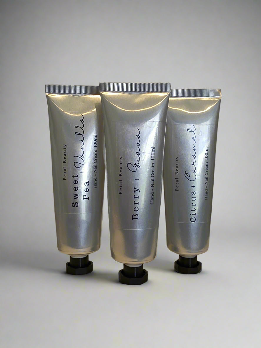 Three silver tubes of hand lotion with black text on a white background
